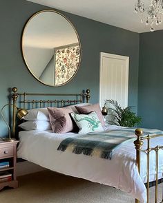 a bed room with a neatly made bed and a round mirror on the wall above it