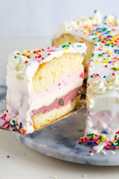 a piece of cake with white frosting and sprinkles on a plate