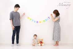 a man and woman standing next to each other near a wall with a happy birthday banner on it