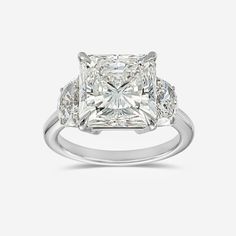 a cushion cut diamond ring with three side stones on the band and shoulders, set in white gold