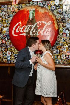 a man and woman kissing in front of a coca - cola sign at a bar