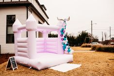 an inflatable bouncy house with balloons on the ground and a sign next to it