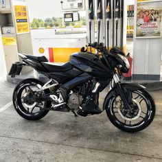 a black motorcycle parked in front of a gas station with no one on it's bike