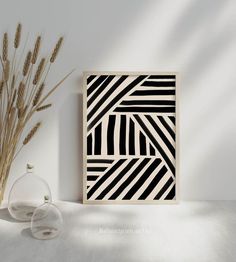 a black and white art piece sitting on top of a table next to a vase