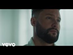 a man with a beard standing in front of a window