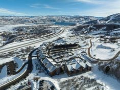 an aerial view of a resort surrounded by snow covered mountains and roads in the distance