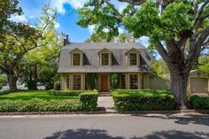 a house with hedges in front of it and trees on the side of the street