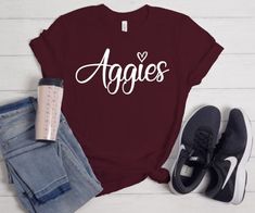 Aggies T-shirt is a great way to represent your school in style! Shirts are unisex sizes, size down for a more fitted look Fitted School Spirit T-shirt With Letter Print, Fitted T-shirt With Letter Print For School Spirit, Fitted Pre-shrunk College T-shirt, Fitted Pre-shrunk T-shirt For College, Casual Name Print T-shirt For Fall, Casual Fall T-shirt With Name Print, Casual Fitted T-shirt With Team Name, Fitted School Spirit T-shirt For College, Casual Tops For College Events In Fall