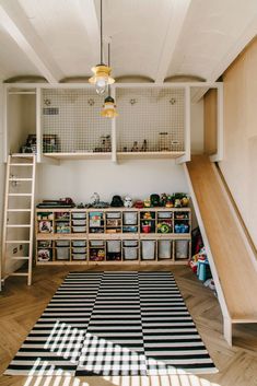 a playroom with shelves, ladders and bins on the floor next to a black and white striped rug