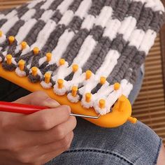 a close up of a person holding a toothbrush and comb with knitted material on it