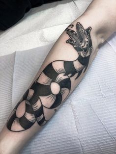 a black and white tattoo on the arm of a person with a snake in it