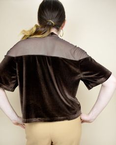 a woman with her back to the camera, wearing a brown shirt and tan pants