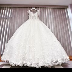 a white wedding dress hanging on a window sill in front of a striped wall