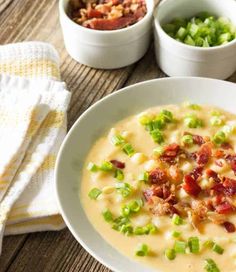 a white bowl filled with soup next to two bowls of peas and other food items