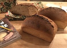 three loaves of bread sitting on top of a wooden table next to a book