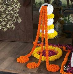 an orange and yellow flower arrangement on display in front of a glass case with other decorations