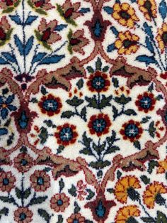 an old rug with colorful flowers and leaves on white ground, closeup view from the top