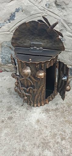 an old metal box sitting on top of a cement floor next to a stone wall