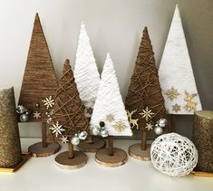 christmas trees made out of yarn and wood are sitting on a shelf next to other decorations