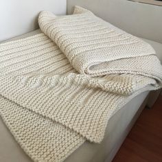 a white blanket is folded on top of a bed