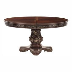 an oval dining table with ornate carvings on the top and base, in dark wood