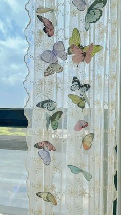 a curtain with butterflies hanging from it's side, in front of a window