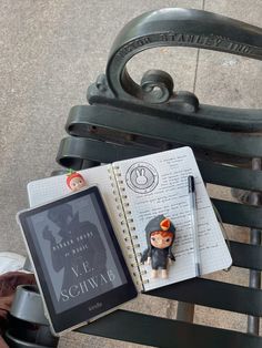 an open notebook with a small figurine sitting on top of it next to a book