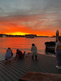 people sitting on a dock watching the sun set