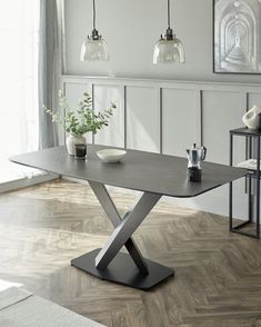 a modern dining table with two hanging lights above it and vases on the side