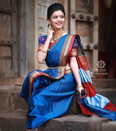 a woman in a blue and red sari sitting on steps with her hand under her chin