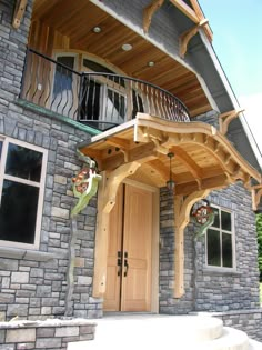 the front entrance to a house with wooden doors and railings on both sides, surrounded by stone steps