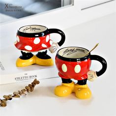 two mickey mouse coffee mugs sitting next to each other