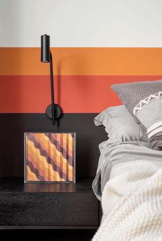 a bedroom with an orange and red striped wall next to a nightstand on a black night stand