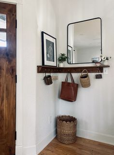 there is a mirror and some baskets on the wall in this room with wood flooring