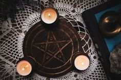 some candles are sitting on a doily with a pentagram