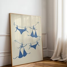 an art piece with blue bras hanging on a line in front of a window