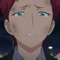 a man with red hair and green eyes stares at the camera in front of a cityscape