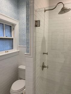 a white toilet sitting next to a walk in shower