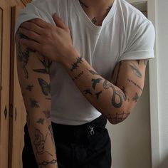 a man with many tattoos on his arm and arms is standing in front of a door