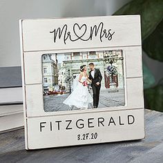 a wedding picture frame with a bride and groom in the background on a wooden table