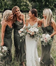 three bridesmaids standing in the grass with their bouquets smiling at each other