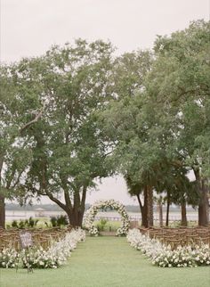 an outdoor ceremony setup with white flowers and greenery on the grass, surrounded by trees