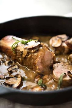 a pan filled with meat and mushrooms covered in gravy