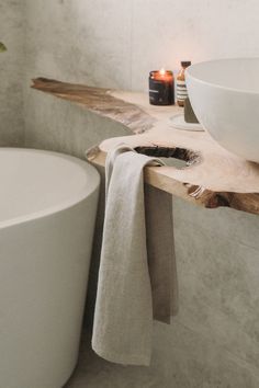 a white bowl sitting on top of a wooden counter next to a bath room sink