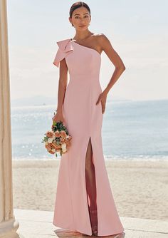 a woman in a pink dress standing on the beach