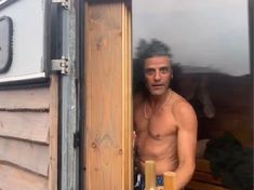 a shirtless man standing in the doorway of a trailer