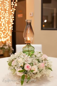 a vase filled with flowers sitting on top of a white table covered in lights and greenery