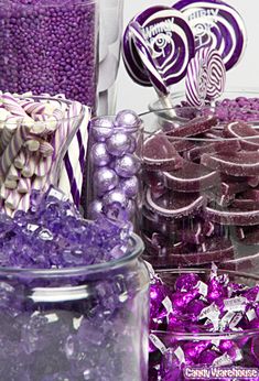 purple and white candy is displayed in glass bowls on a table with other candies