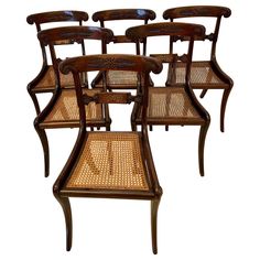 six wooden chairs with cane seats on them