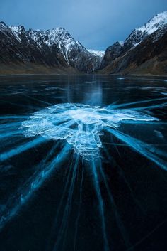 an icy lake surrounded by snow covered mountains